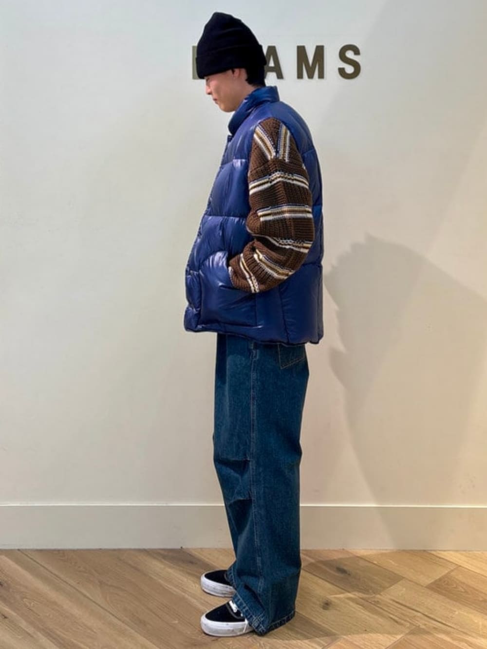 ブラウン系のニット/セーター、ブルー系のダウンベスト、ブルー系のデニムパンツを着用したメンズの冬コーディネートの2枚目の写真