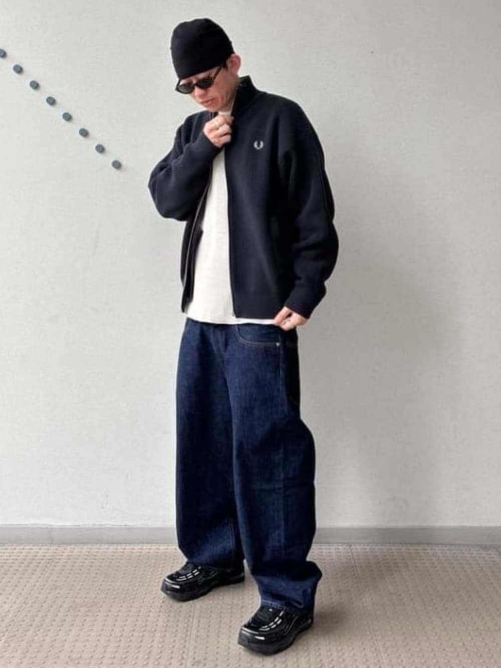 ブルー系のデニムパンツ、ブラック系のカーディガン/ボレロ、ベージュ系のTシャツ/カットソーを着用したメンズの秋コーディネートの2枚目の写真