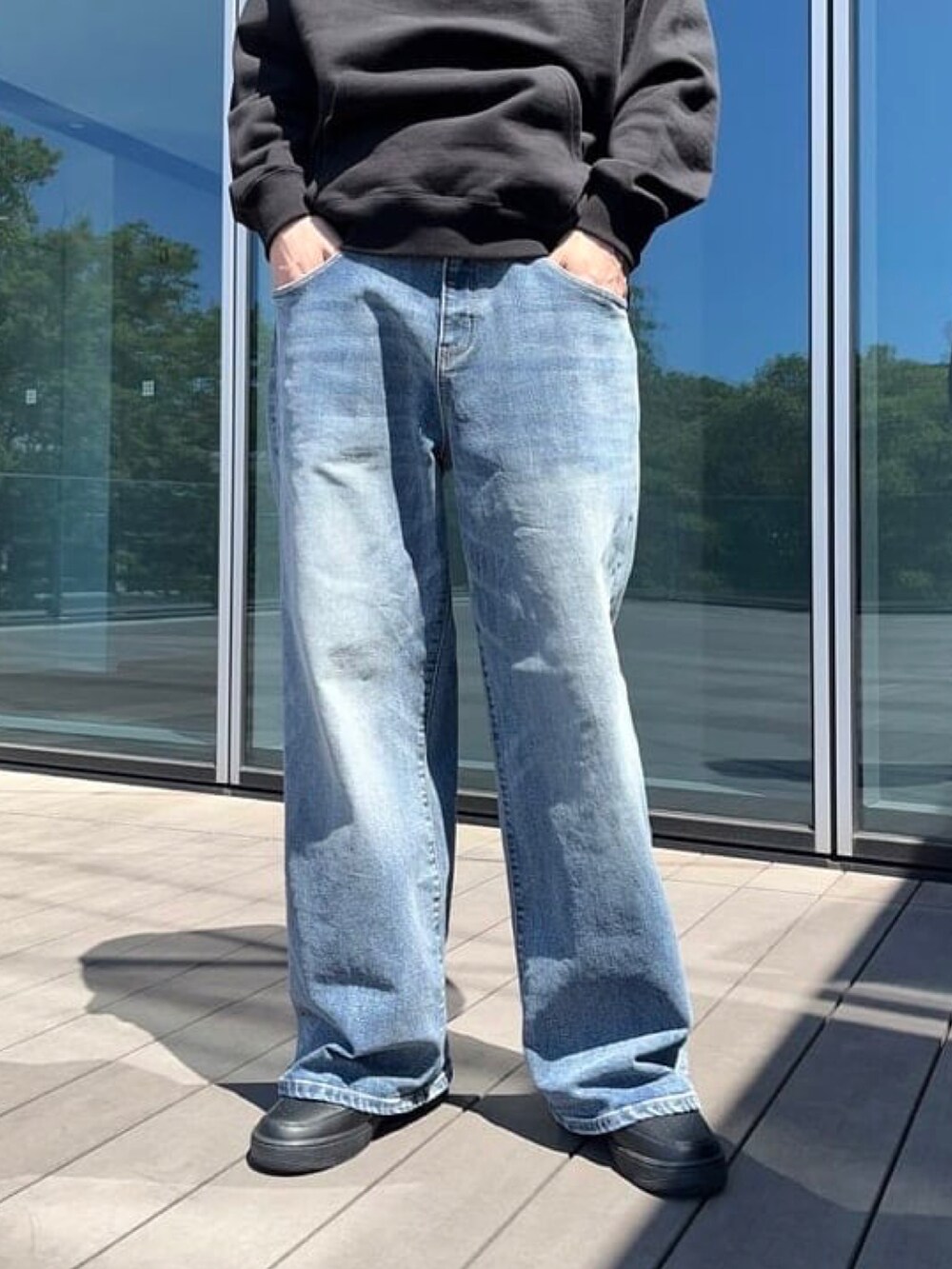 ブラック系のパーカー、ブルー系のデニムパンツ、ブラック系のスニーカーを着用したメンズの秋コーディネートの5枚目の写真