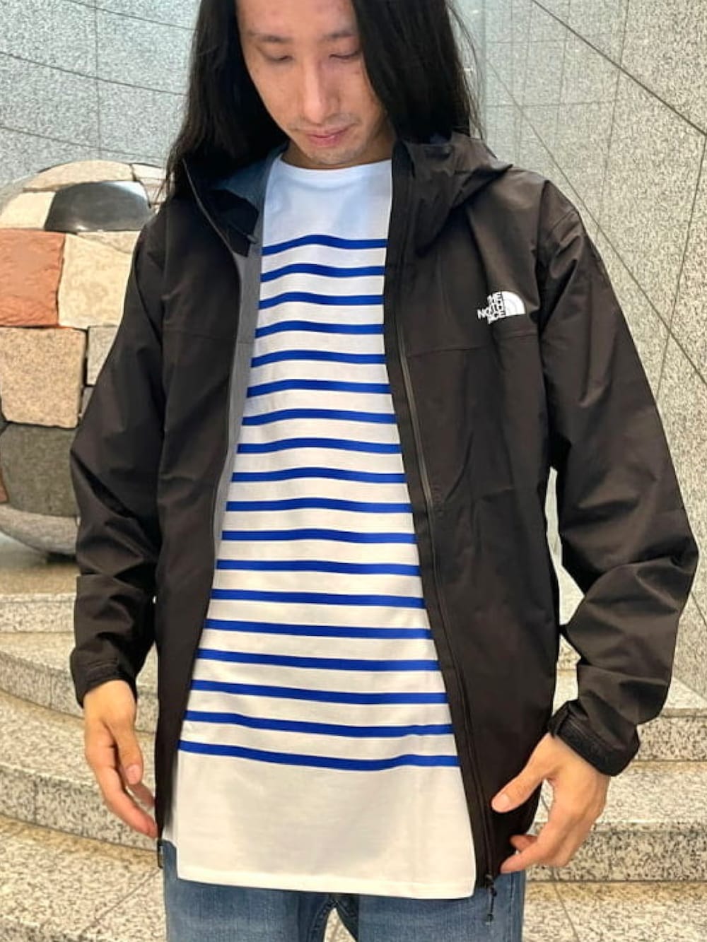 ブラック系のブルゾン、ホワイト系のTシャツ/カットソー、ブルー系のデニムパンツを着用したメンズの春コーディネートの3枚目の写真