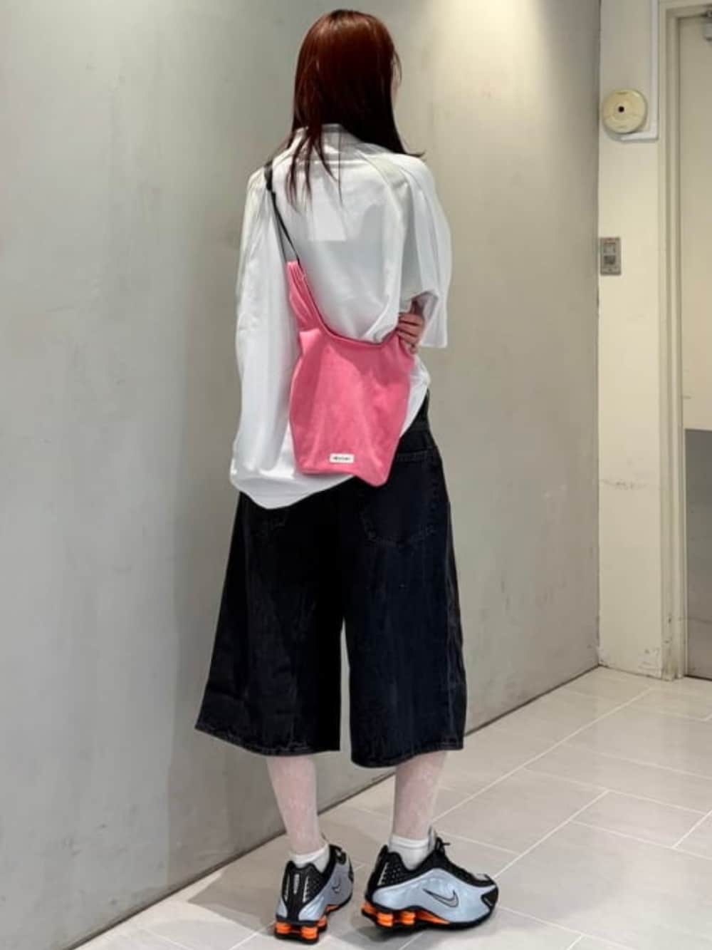 ブラック系のデニムパンツ、ピンク系のハンドバッグ、ホワイト系のTシャツ/カットソーを着用したレディースの夏コーディネートの2枚目の写真