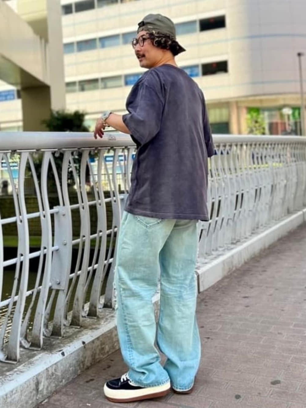 ブルー系のデニムパンツ、ブラック系のTシャツ/カットソー、ブラック系のスニーカーを着用したメンズの春コーディネートの2枚目の写真