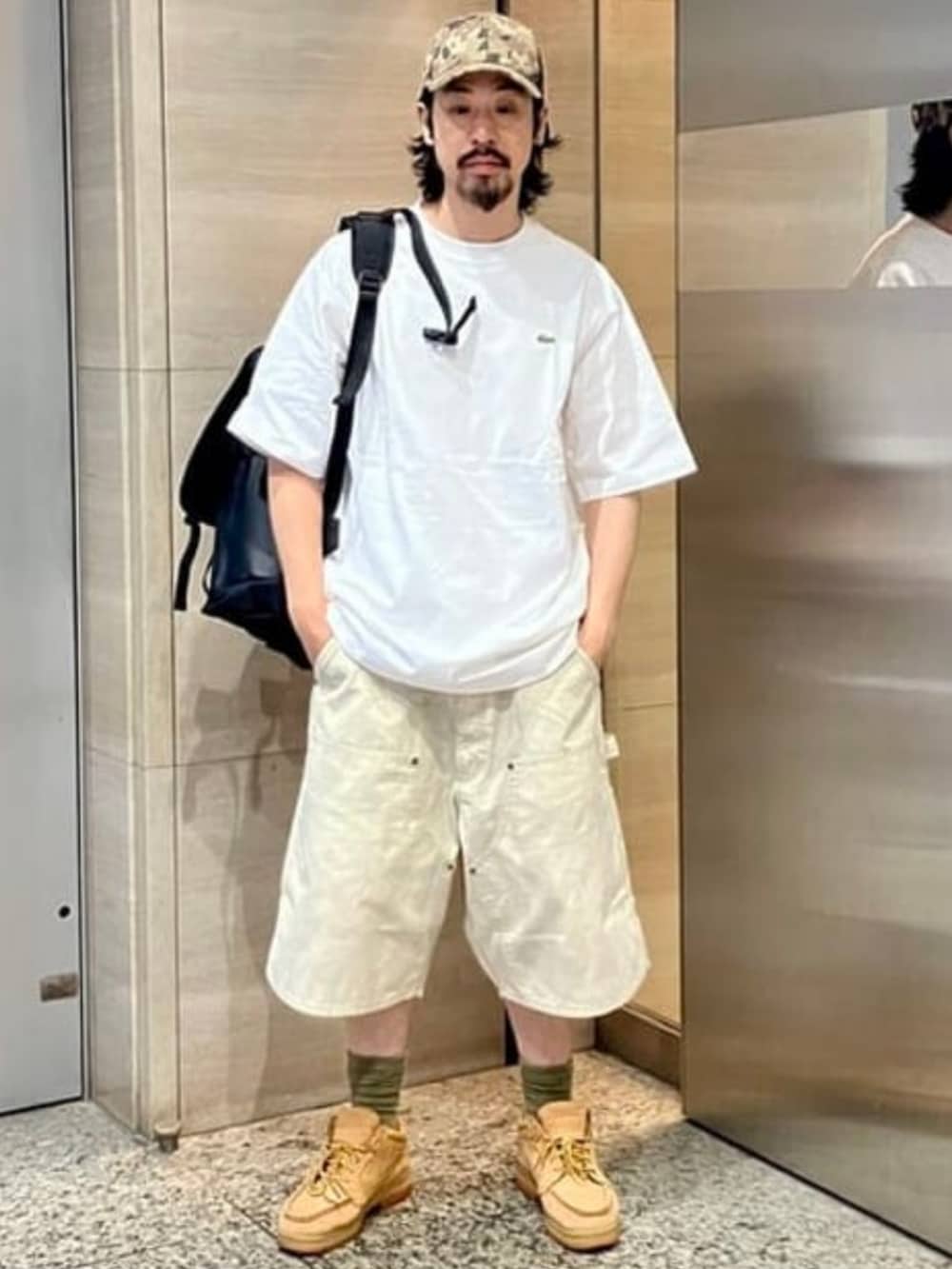 ベージュ系のその他パンツ、ホワイト系のTシャツ/カットソー、ブラック系のバックパック/リュックを着用したメンズの夏コーディネートの2枚目の写真