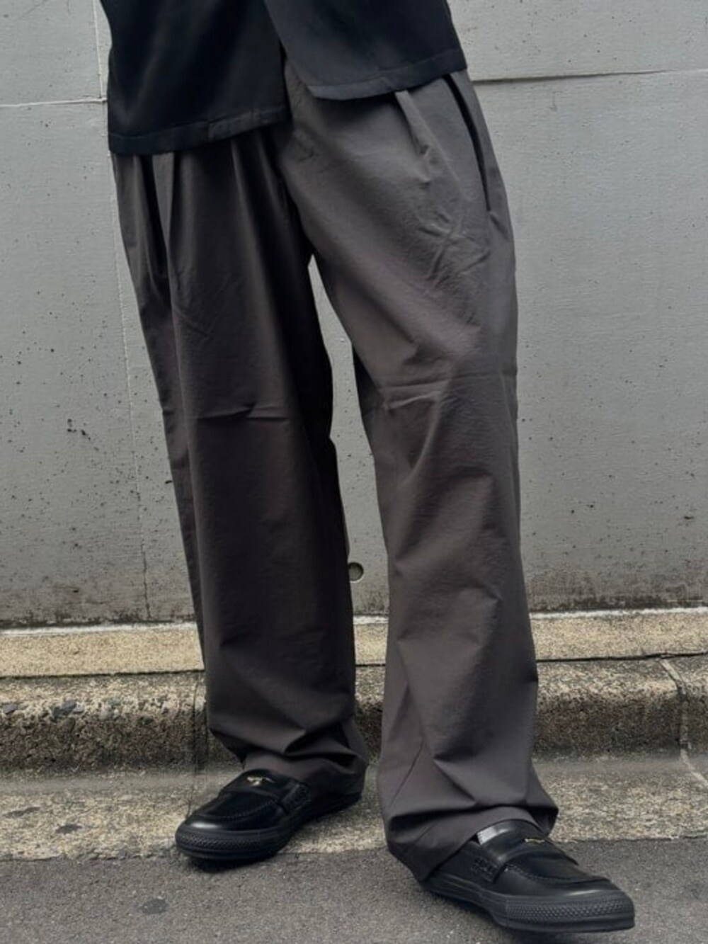 グレー系のスラックス、ブラック系のキャップを着用したメンズの夏コーディネートの4枚目の写真