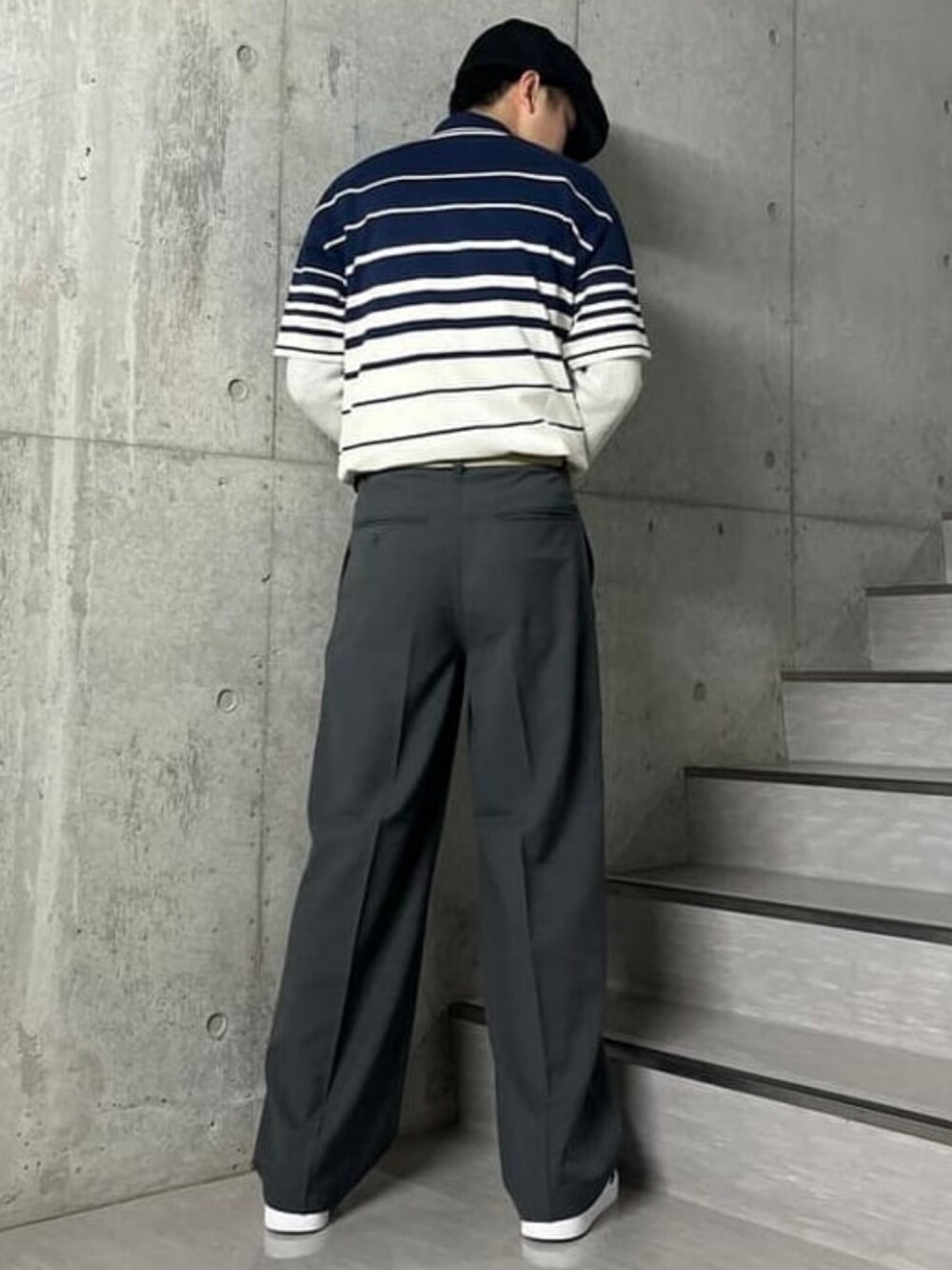 グレー系のスラックス、ブルー系のポロシャツ、ホワイト系のスニーカーを着用したメンズの春コーディネートの2枚目の写真