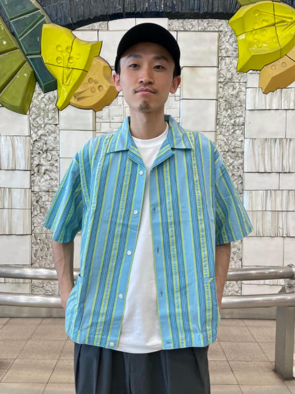 グリーン系のシャツ/ブラウス、グレー系のスラックス、ホワイト系のTシャツ/カットソーを着用したメンズの春コーディネートの2枚目の写真