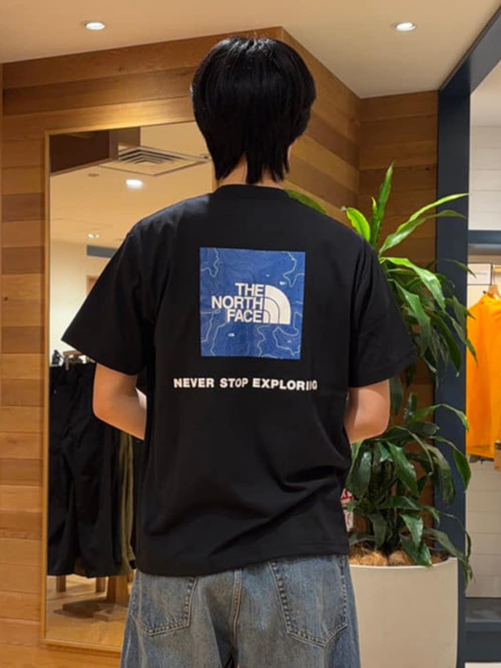 ブルー系のデニムパンツ、ブラック系のTシャツ/カットソー、ブラウン系のスニーカーを着用したメンズの春コーディネートの2枚目の写真
