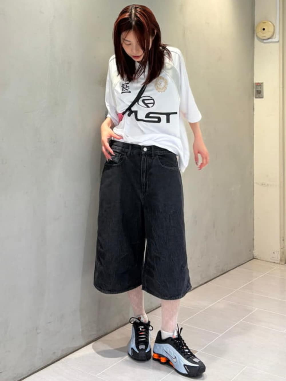 ブラック系のデニムパンツ、ピンク系のハンドバッグ、ホワイト系のTシャツ/カットソーを着用したレディースの夏コーディネートの3枚目の写真
