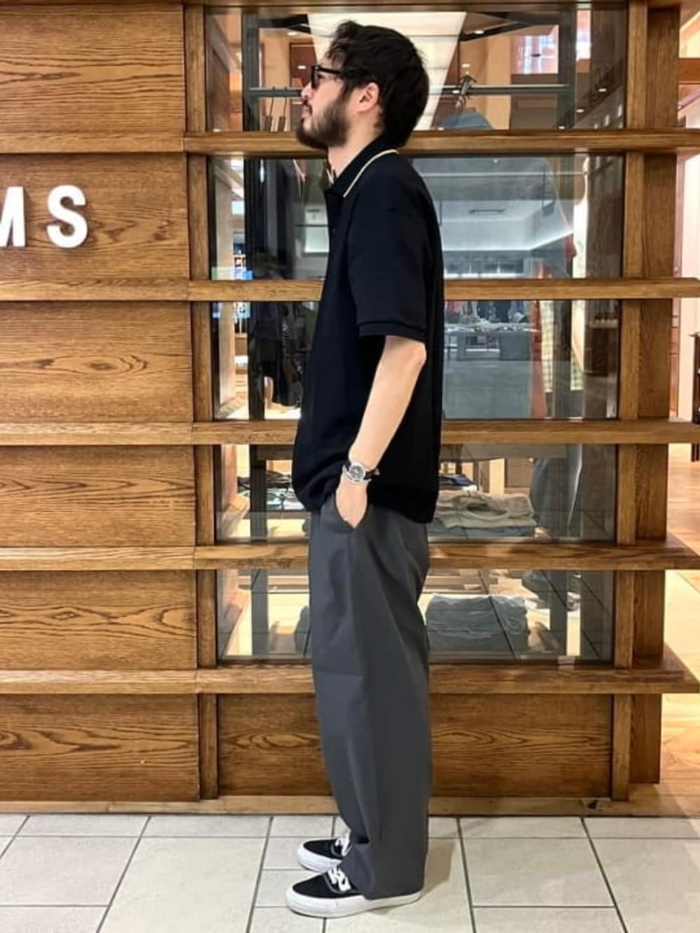 ブラック系のポロシャツ、ブラック系のTシャツ/カットソー、グレー系のスラックスを着用したメンズの夏コーディネートの2枚目の写真