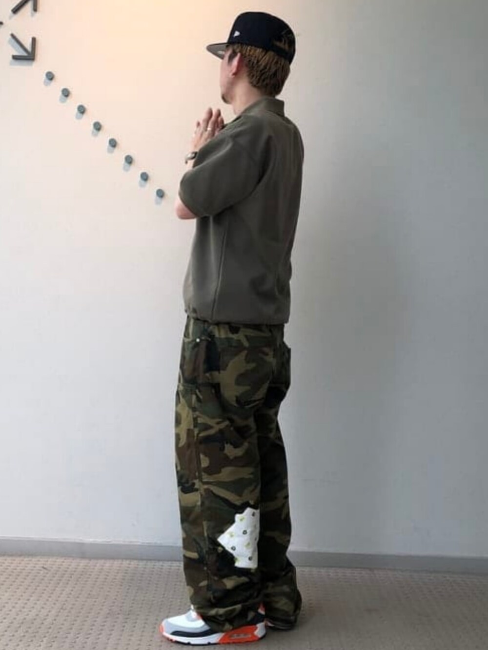 ベージュ系のポロシャツ、グレー系のスニーカー、ブルー系のキャップを着用したメンズの夏コーディネートの2枚目の写真