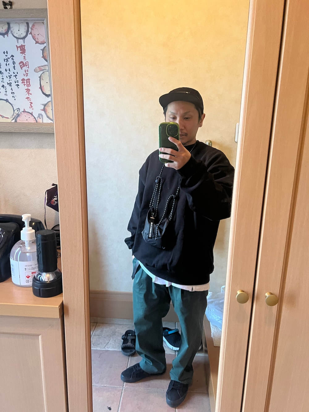 ブラック系のスウェット、グリーン系のチノパンツ、ブラック系のスニーカーを着用したメンズの秋コーディネートの2枚目の写真