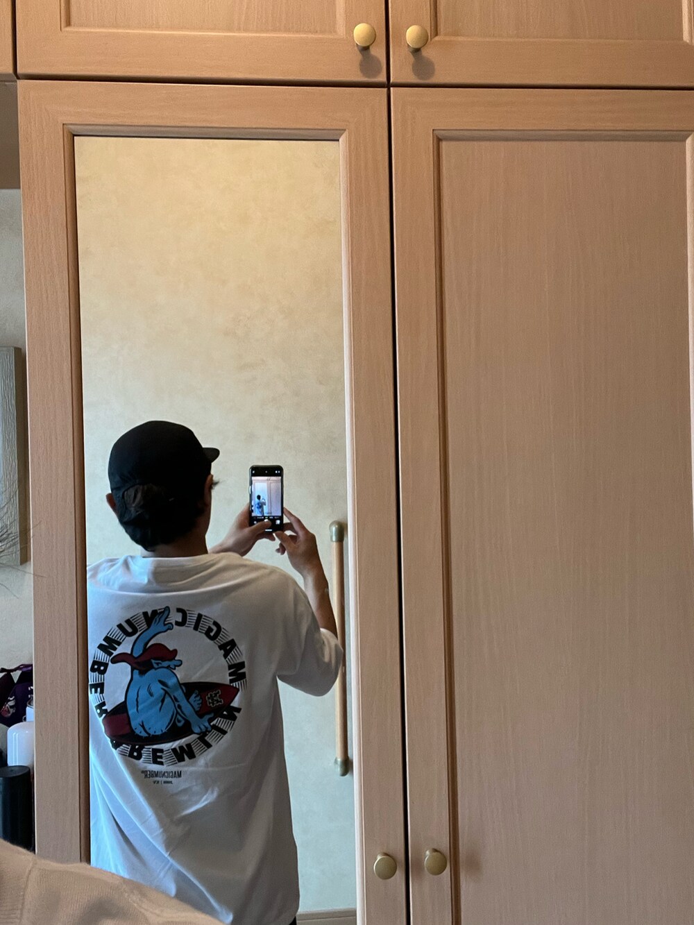 ホワイト系のTシャツ/カットソー、ブラック系のチノパンツ、ブラック系のスニーカーを着用したメンズの夏コーディネートの2枚目の写真