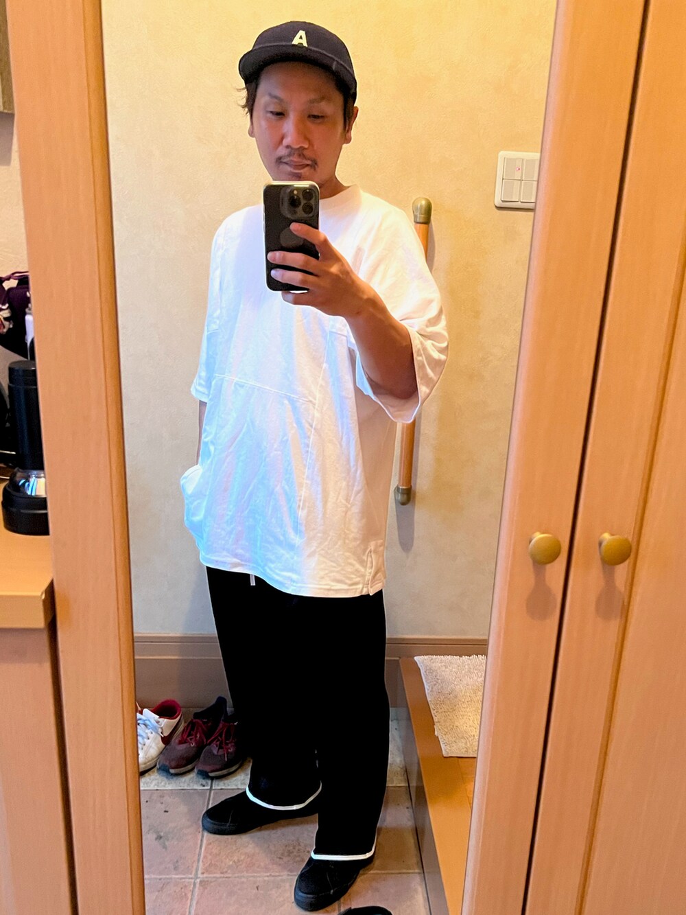 ホワイト系のポロシャツ、ブラック系のその他パンツ、ブラック系のスニーカーを着用したメンズの夏コーディネートの2枚目の写真