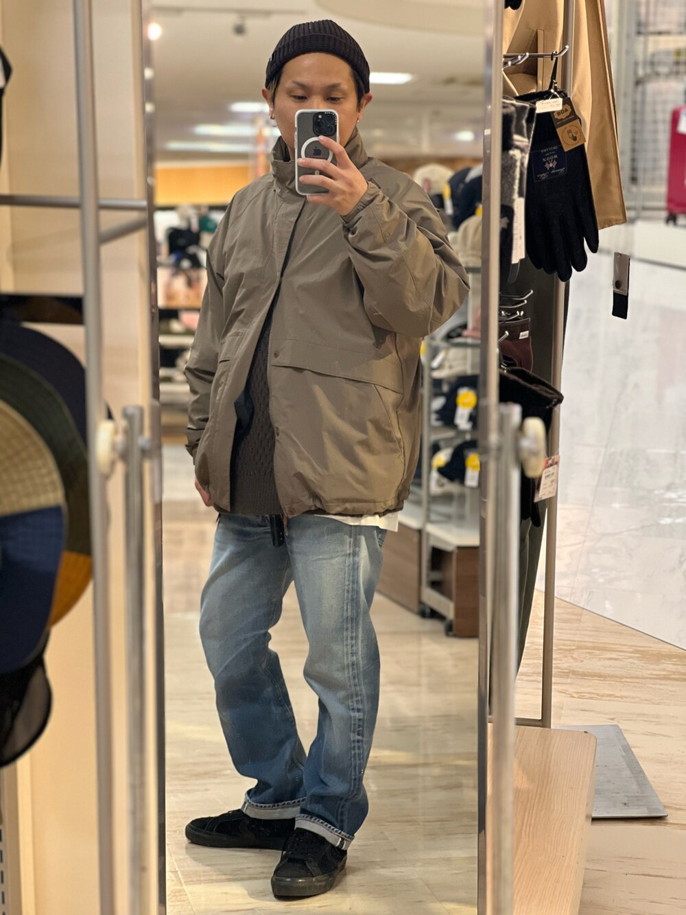 ブラウン系のナイロンジャケット、ブラック系のショルダーバッグ、ブルー系のデニムパンツを着用したメンズの冬コーディネートの2枚目の写真