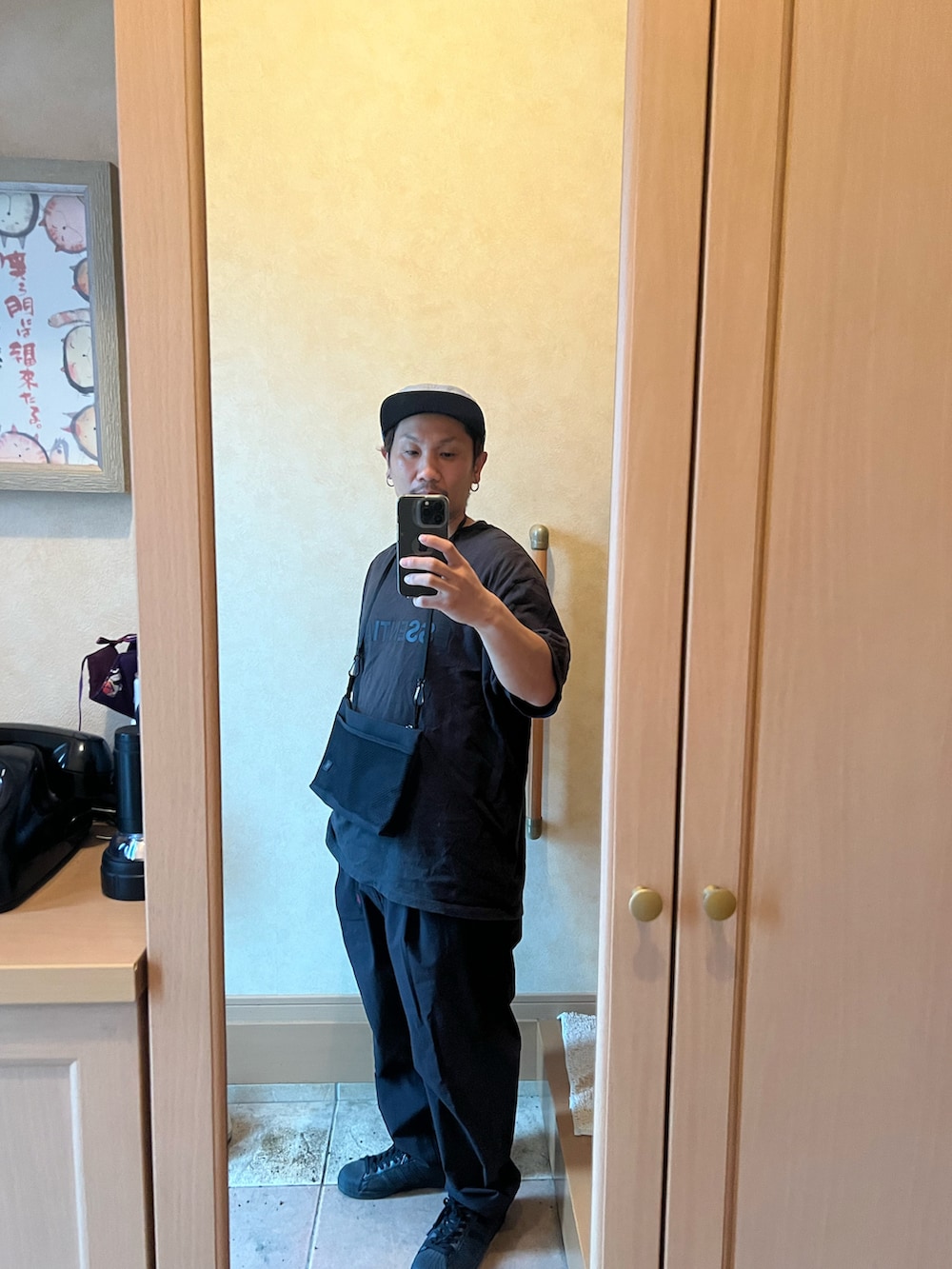 ブラック系のショルダーバッグ、ブラック系のTシャツ/カットソー、ブラック系のパンツを着用したメンズの夏コーディネートの2枚目の写真