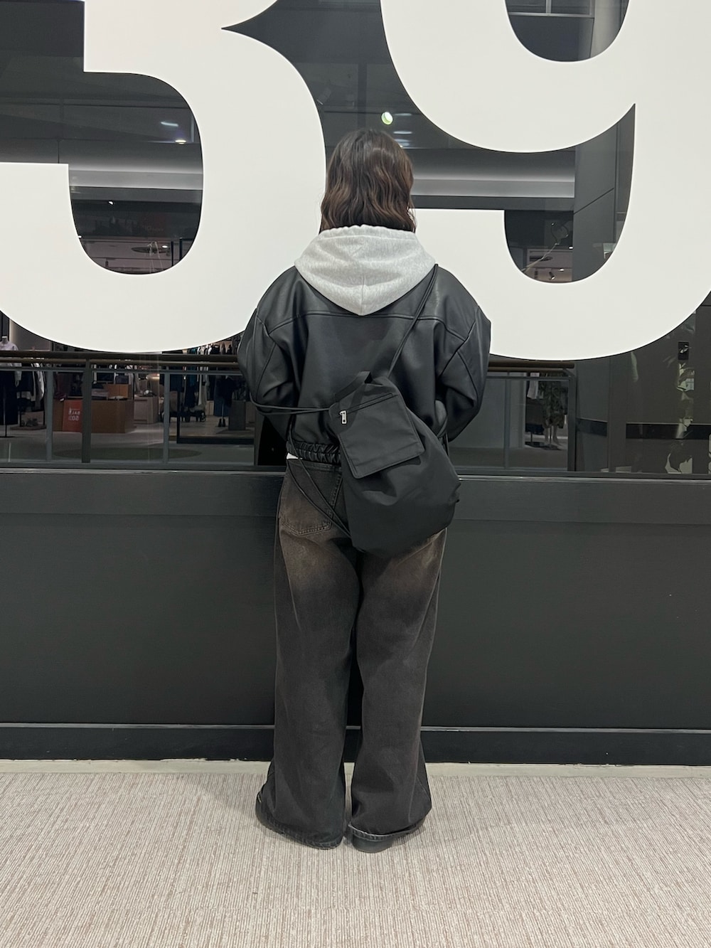 ブラック系のデニムパンツ、ブラック系のライダースジャケット、グレー系のパーカーを着用したレディースの冬コーディネートの3枚目の写真