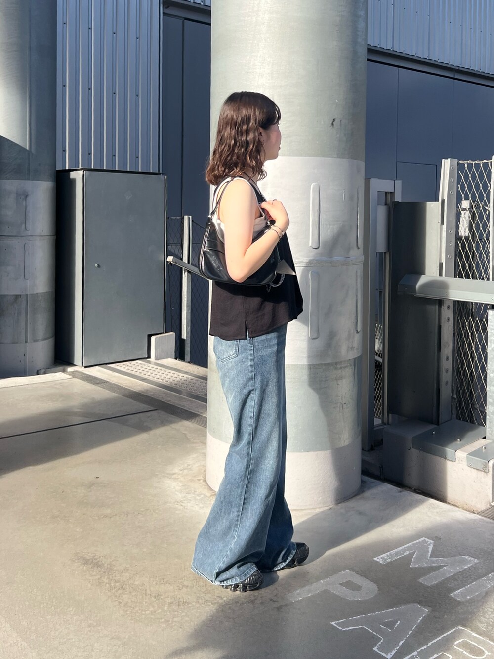 ブルー系のデニムパンツ、ブラック系のキャミソール、ブラック系のハンドバッグを着用したレディースの夏コーディネートの2枚目の写真