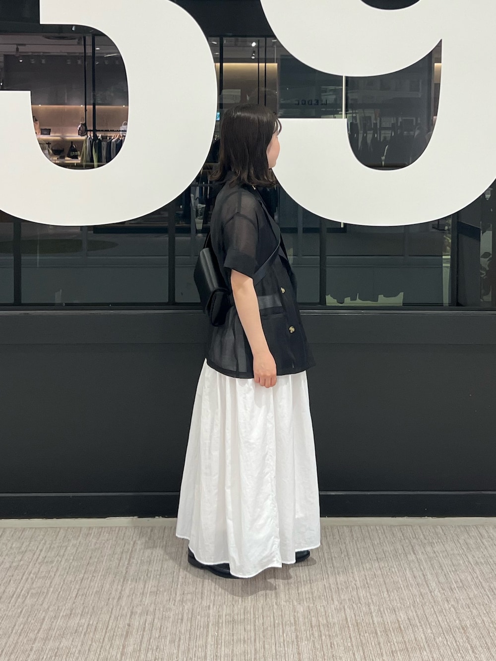 ホワイト系のスカート、ブラック系のテーラードジャケット、ブラック系のボディバッグ/ウエストポーチを着用したレディースの夏コーディネートの2枚目の写真
