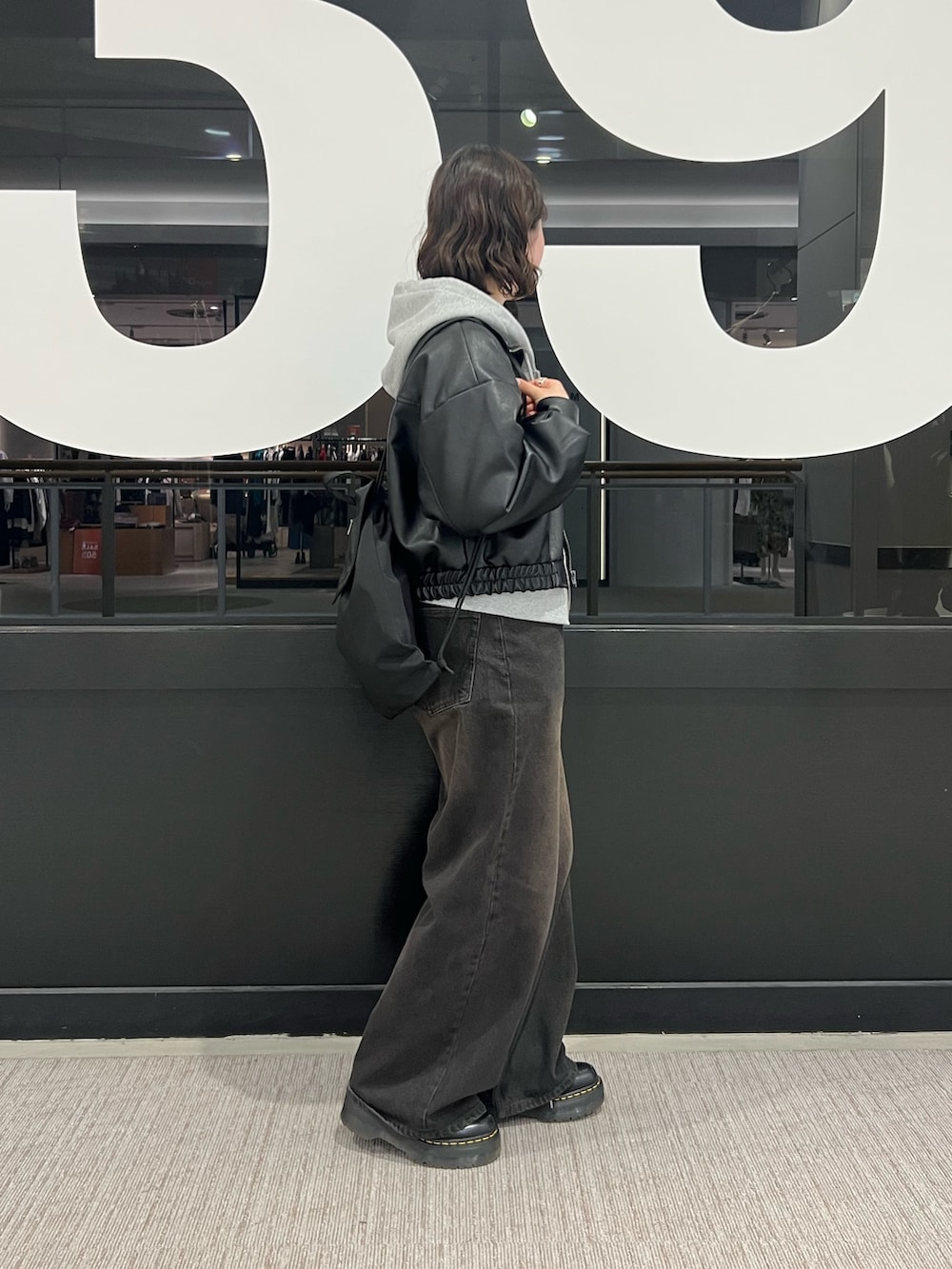 ブラック系のデニムパンツ、ブラック系のライダースジャケット、グレー系のパーカーを着用したレディースの冬コーディネートの2枚目の写真