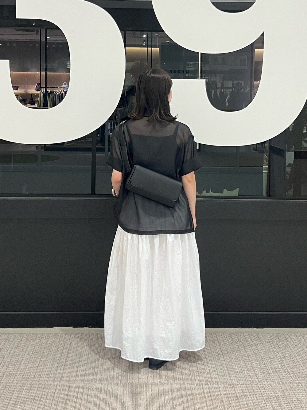 ホワイト系のスカート、ブラック系のテーラードジャケット、ブラック系のボディバッグ/ウエストポーチを着用したレディースの夏コーディネートの3枚目の写真