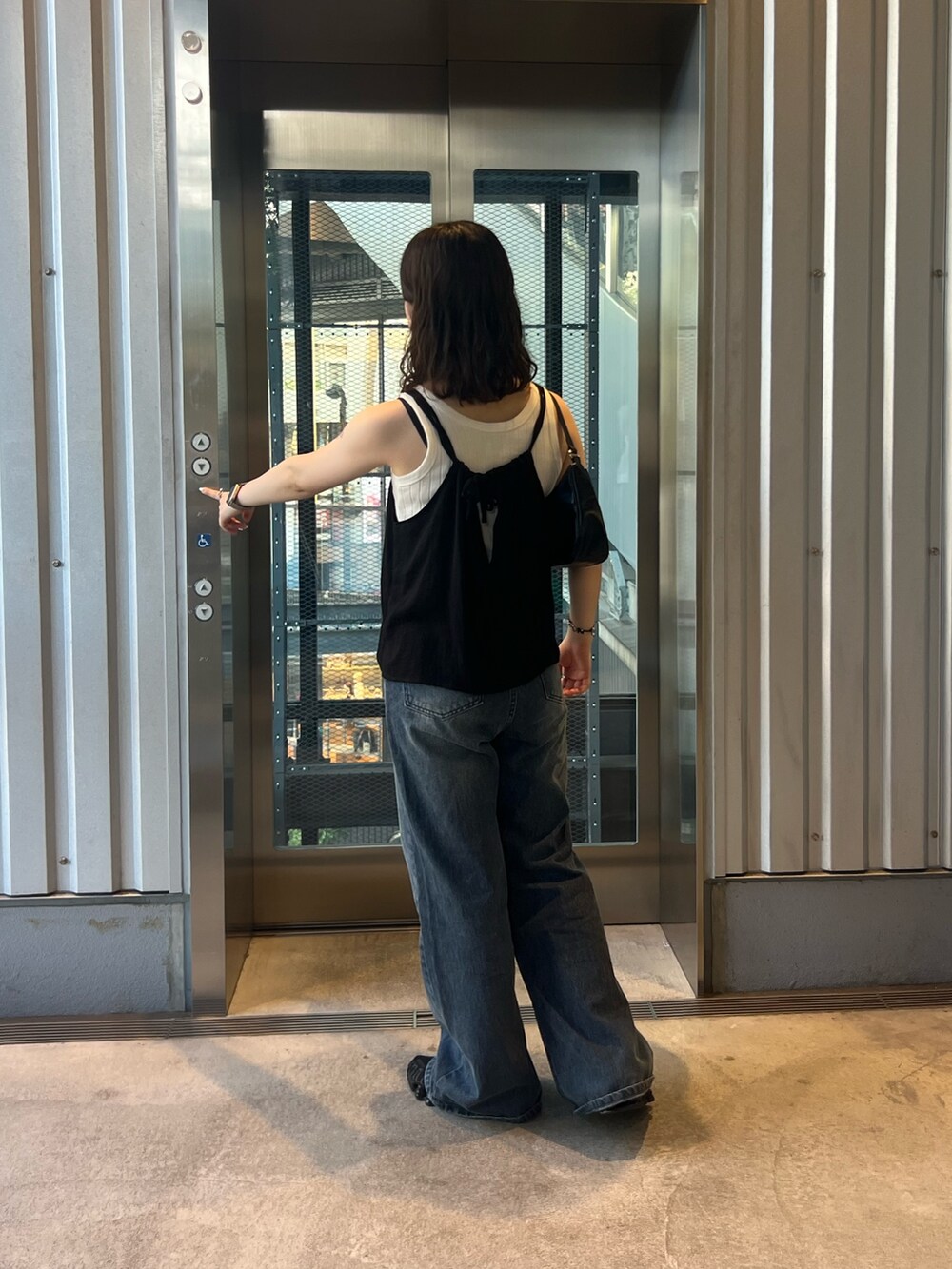 ブルー系のデニムパンツ、ブラック系のキャミソール、ブラック系のハンドバッグを着用したレディースの夏コーディネートの3枚目の写真