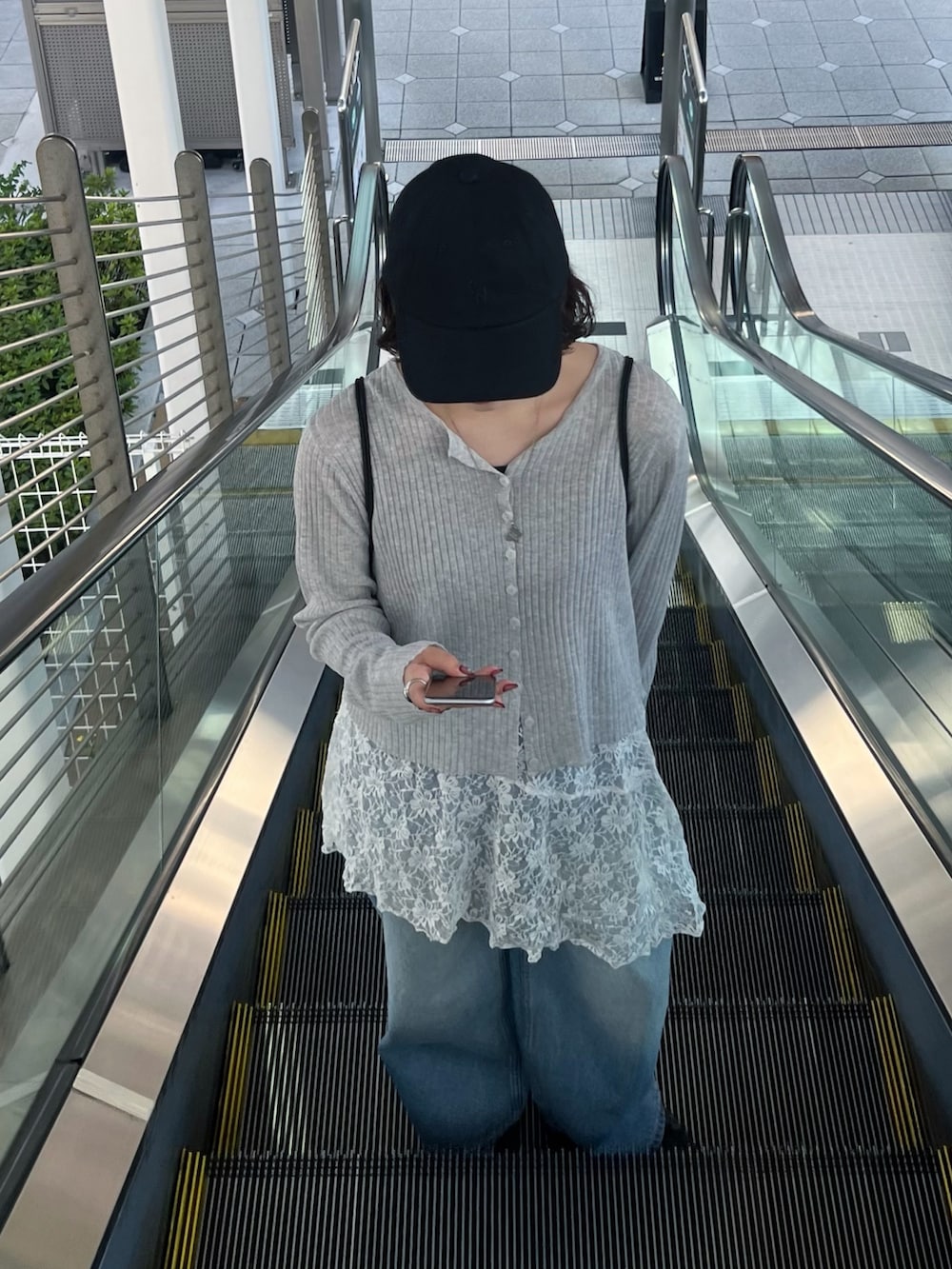 ブルー系のデニムパンツ、グレー系のカーディガン/ボレロ、ブラック系のバックパック/リュックを着用したレディースの春コーディネートの3枚目の写真