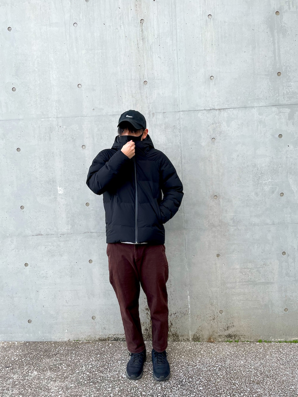 ブラック系のダウンベスト、ブラウン系のパンツ、ホワイト系のスウェットを着用したメンズの冬コーディネートの2枚目の写真