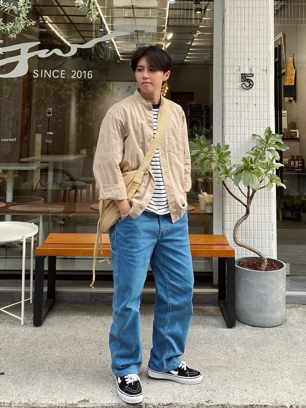 ブラック系のスニーカー、ベージュ系のバッグを着用したレディースの夏コーディネートの2枚目の写真