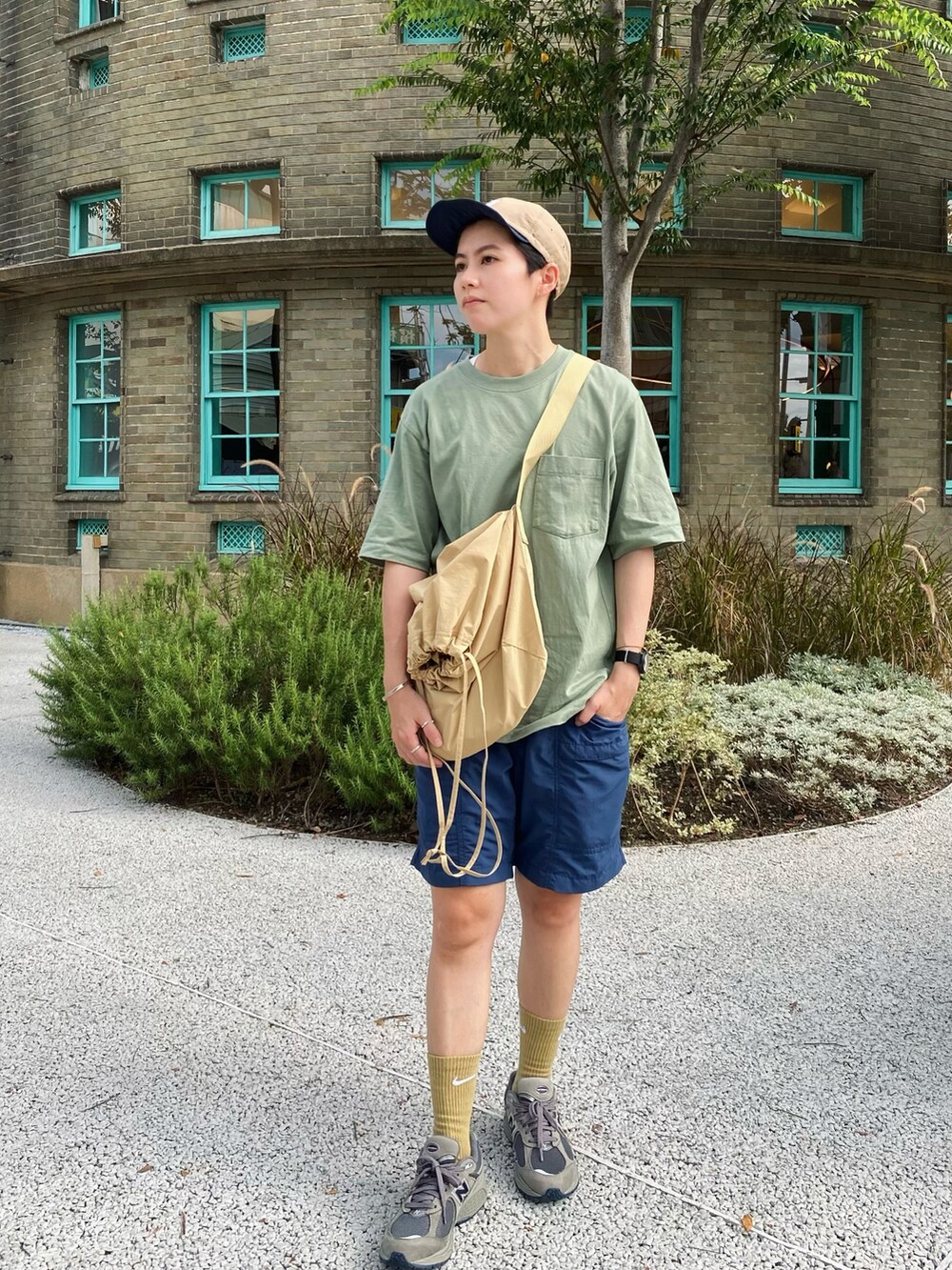 ベージュ系のバッグ、グリーン系のシューズ、ベージュ系の帽子を着用したレディースの夏コーディネートの2枚目の写真