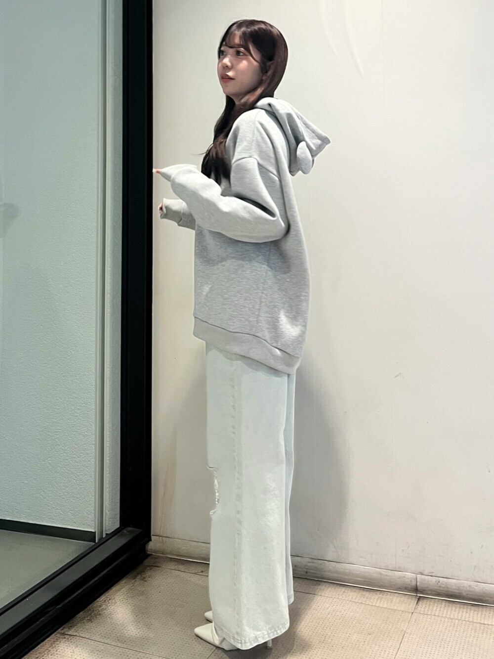 ホワイト系のパンプス、グレー系のスウェット、ブルー系のデニムパンツを着用したレディースの秋コーディネートの2枚目の写真
