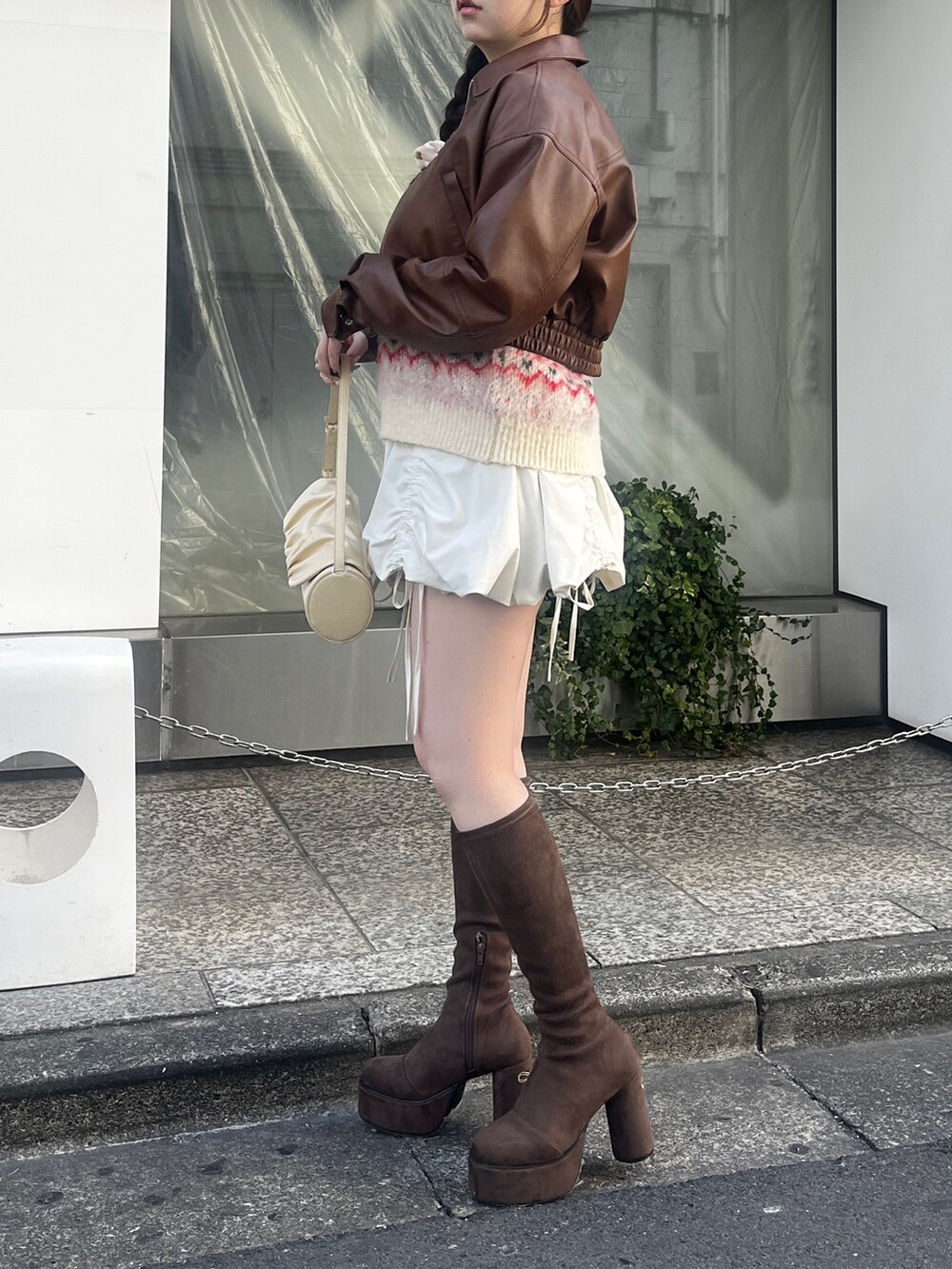 ブラウン系のブルゾン、ホワイト系のニット/セーター、ホワイト系のスカートを着用したレディースの冬コーディネートの2枚目の写真