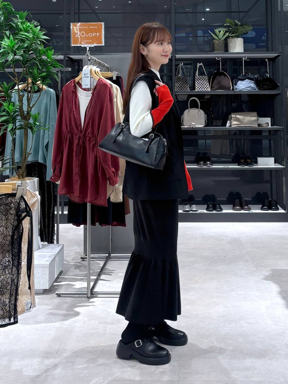 ブラック系のスカート、ホワイト系のニット/セーター、ブラック系のサンダルを着用したレディースの秋コーディネートの3枚目の写真