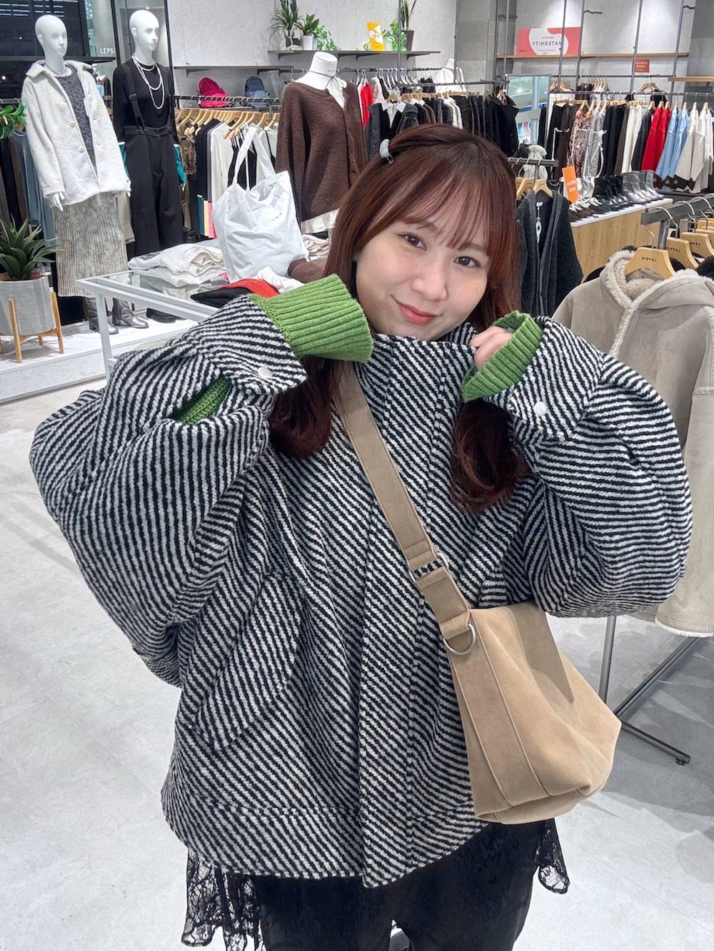 ベージュ系のショルダーバッグ、ブラック系のサンダル、ブラック系のブルゾンを着用したレディースの冬コーディネートの2枚目の写真