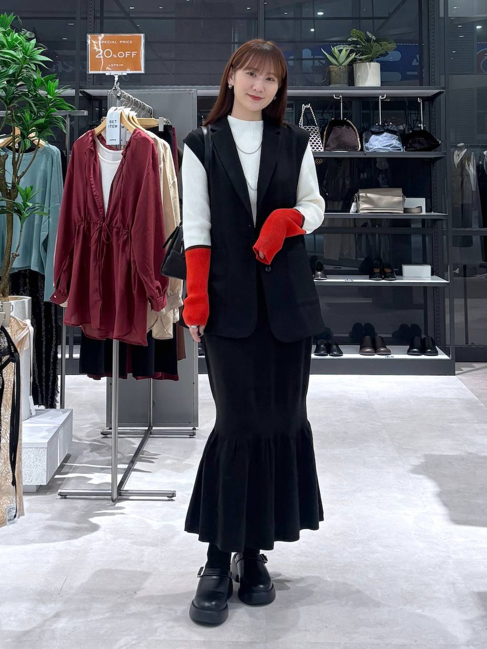 ブラック系のスカート、ホワイト系のニット/セーター、ブラック系のサンダルを着用したレディースの秋コーディネートの2枚目の写真