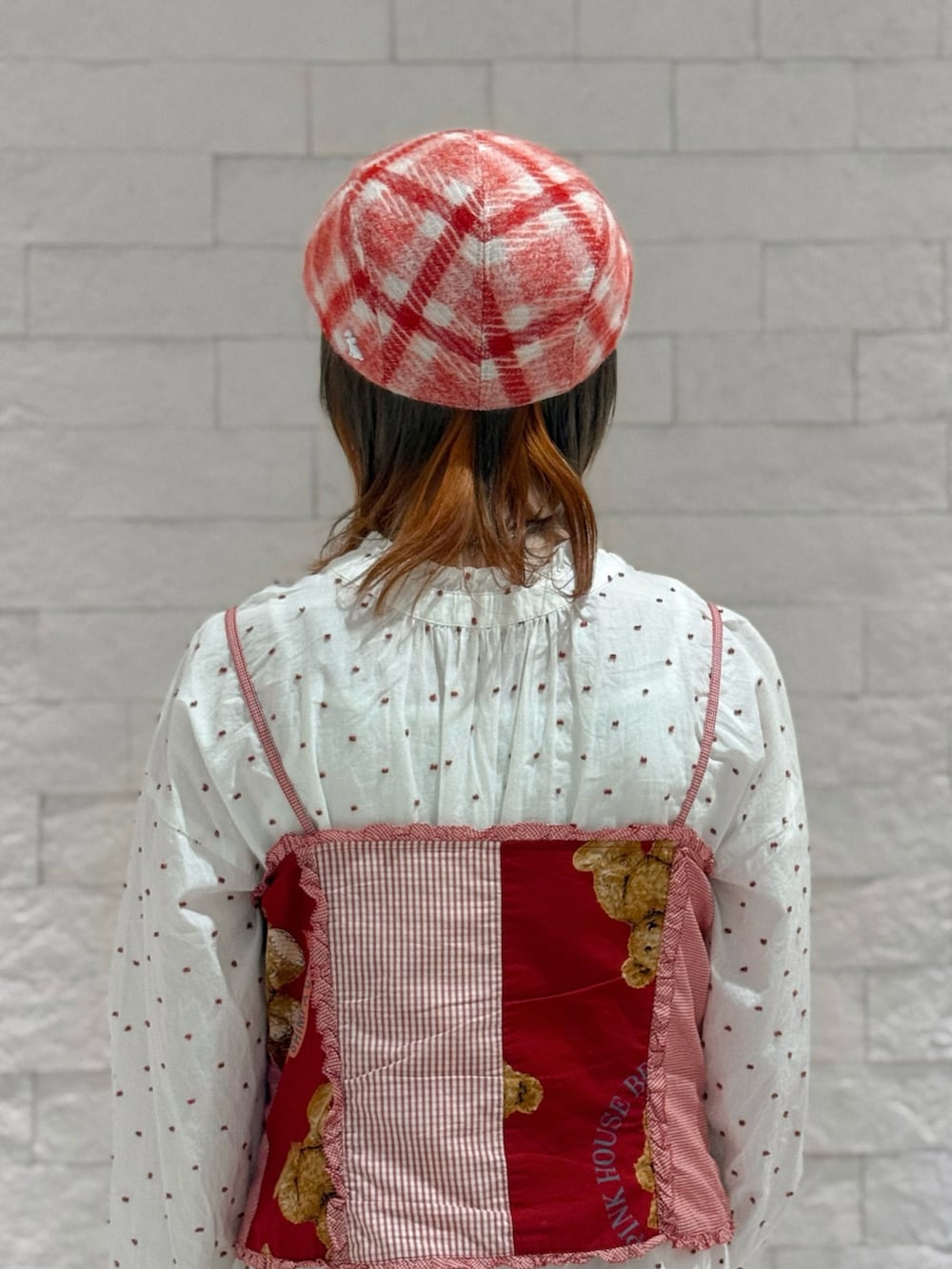 レッド系のベスト、ホワイト系のワンピース、ブラウン系のサンダルを着用したレディースの秋コーディネートの3枚目の写真