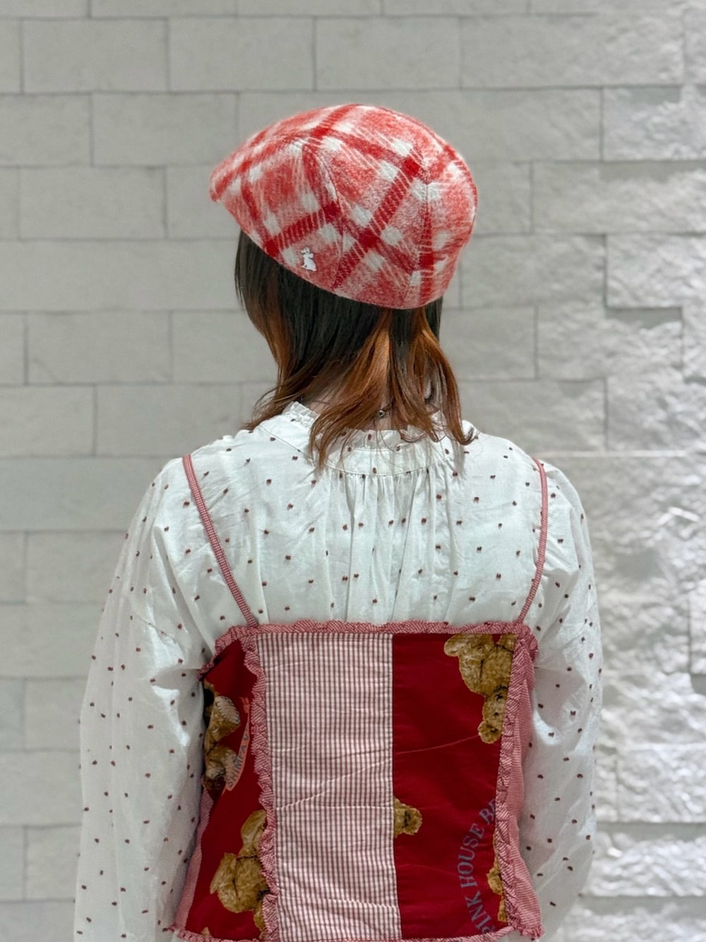 レッド系のベスト、ホワイト系のワンピース、ブラウン系のサンダルを着用したレディースの秋コーディネートの5枚目の写真