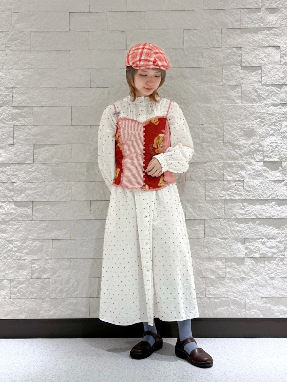 レッド系のベスト、ホワイト系のワンピース、ブラウン系のサンダルを着用したレディースの秋コーディネートの7枚目の写真