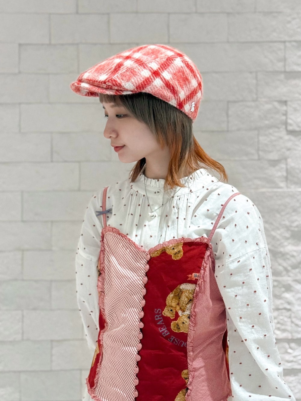 レッド系のベスト、ホワイト系のワンピース、ブラウン系のサンダルを着用したレディースの秋コーディネートの2枚目の写真