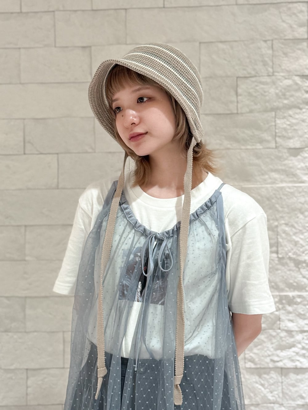 グレー系のパンツ、グレー系のスニーカー、ブラウン系のハットを着用したレディースの夏コーディネートの3枚目の写真