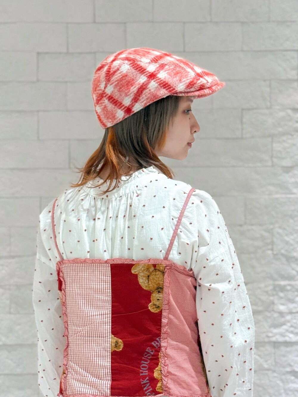 レッド系のベスト、ホワイト系のワンピース、ブラウン系のサンダルを着用したレディースの秋コーディネートの6枚目の写真