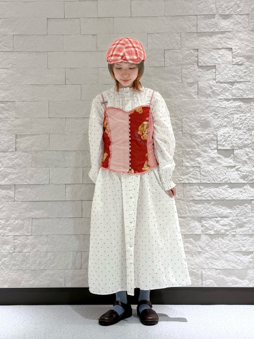 レッド系のベスト、ホワイト系のワンピース、ブラウン系のサンダルを着用したレディースの秋コーディネートの4枚目の写真