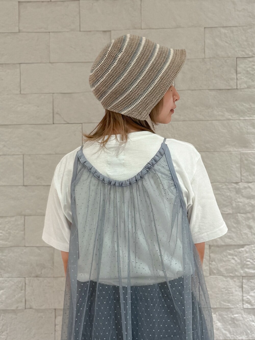 グレー系のパンツ、グレー系のスニーカー、ブラウン系のハットを着用したレディースの夏コーディネートの4枚目の写真