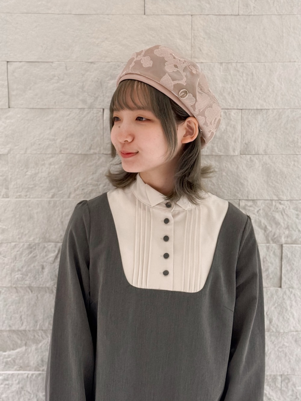 グレー系のワンピース、ホワイト系のシューズ、ピンク系のハンチング/ベレー帽を着用したレディースの春コーディネートの2枚目の写真