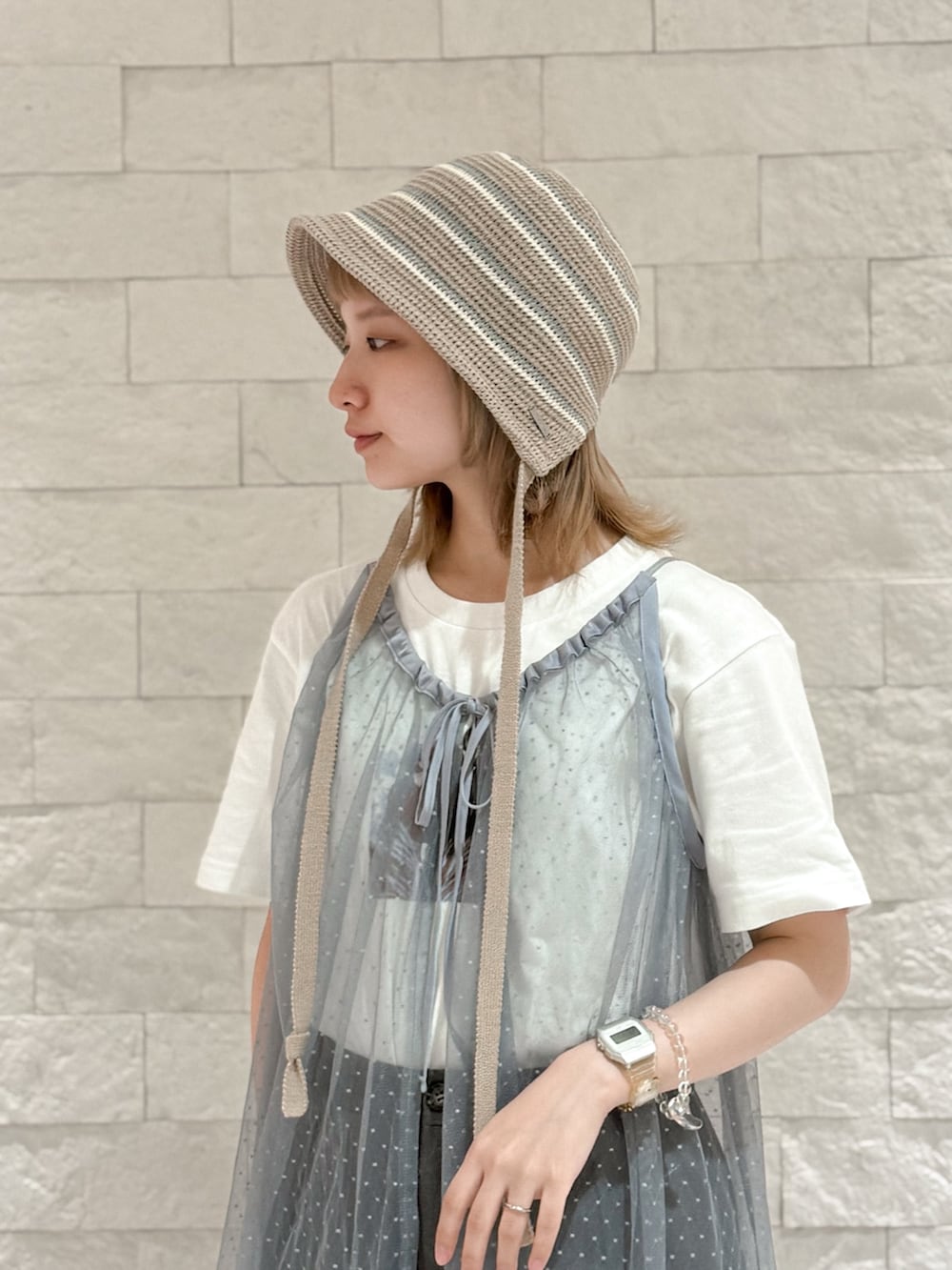 グレー系のパンツ、グレー系のスニーカー、ブラウン系のハットを着用したレディースの夏コーディネートの2枚目の写真