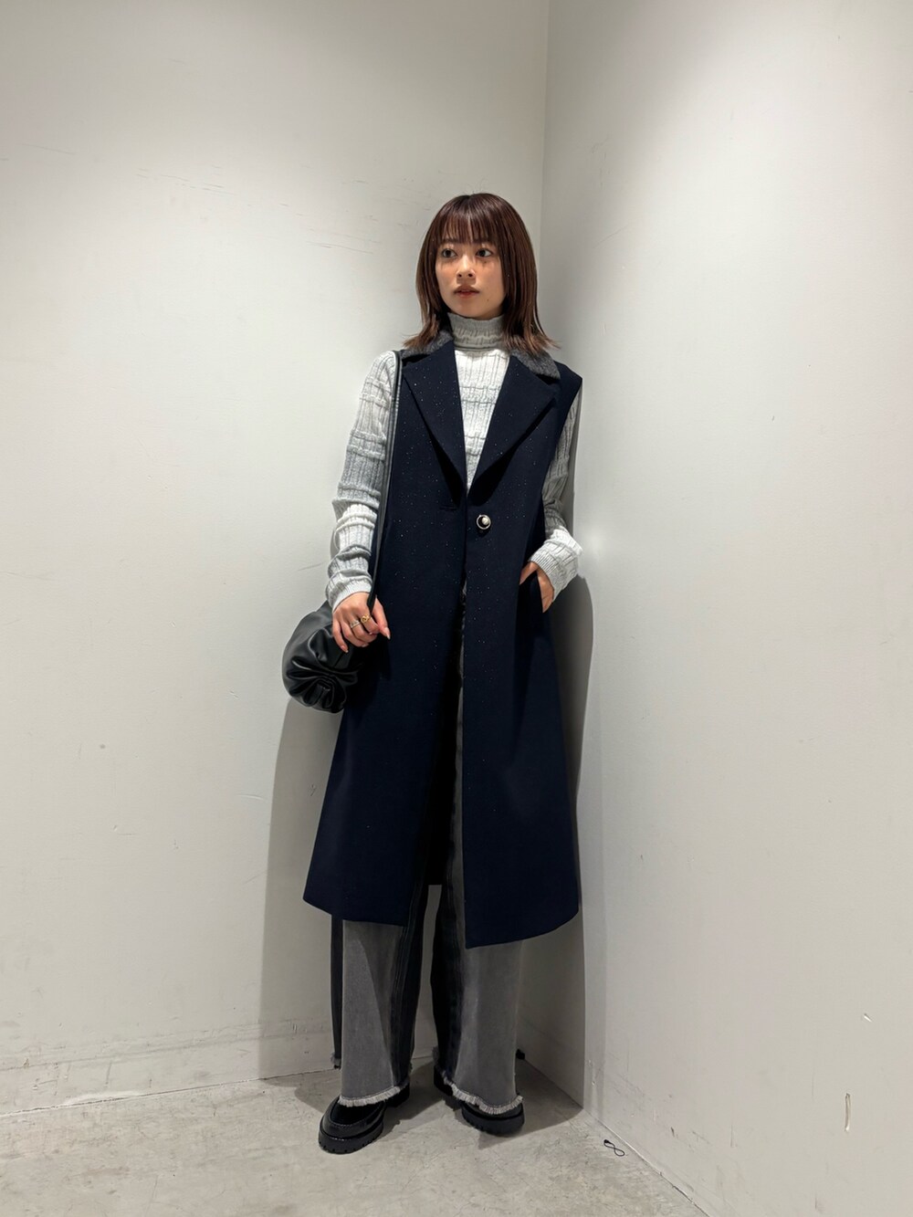 グレー系のニット/セーター、ブルー系のベスト、グレー系のデニムパンツを着用したレディースの秋コーディネートの2枚目の写真