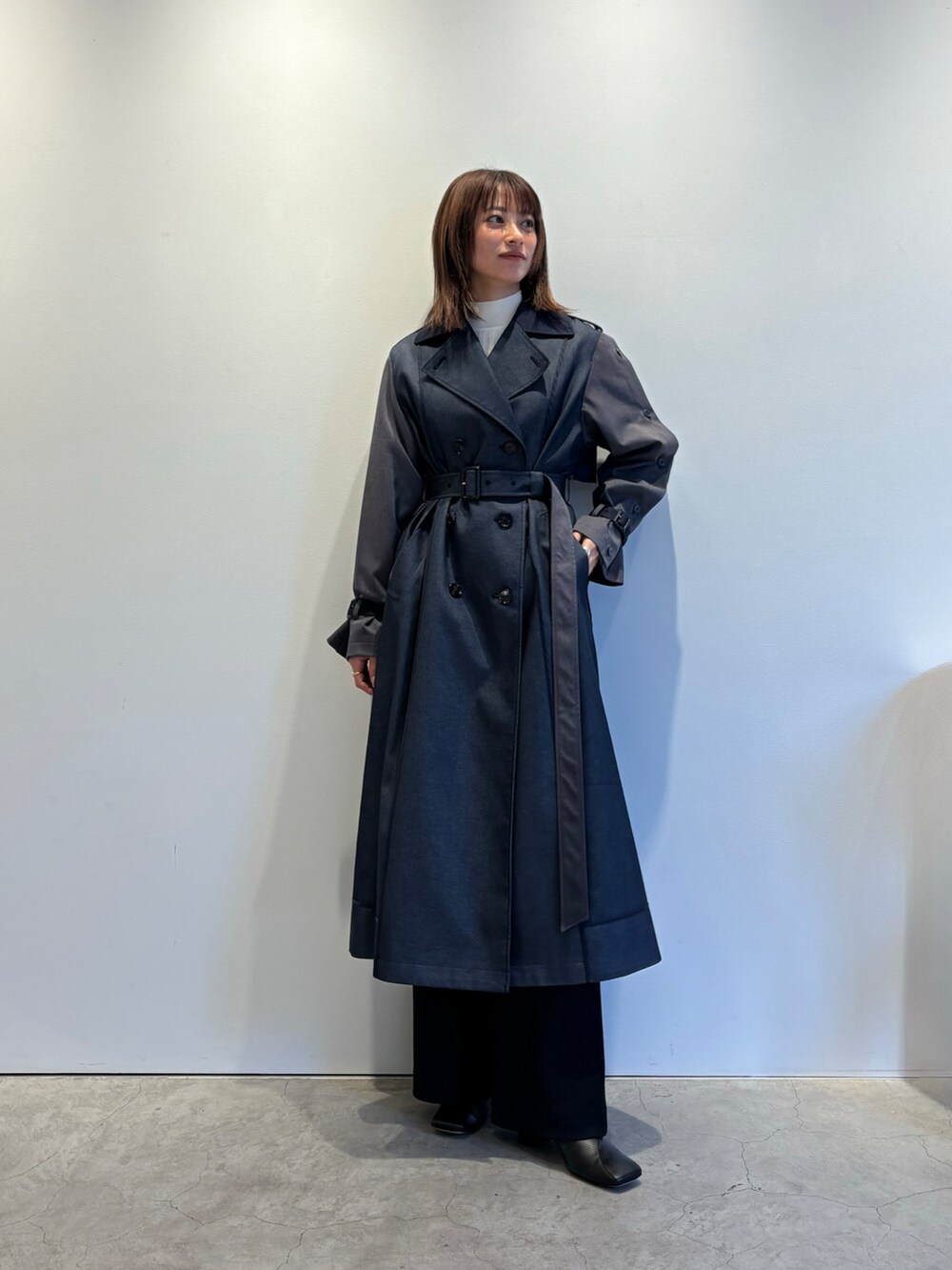 ブルー系のトレンチコート、ホワイト系のニット/セーター、ブラック系のその他パンツを着用したレディースの秋コーディネートの2枚目の写真