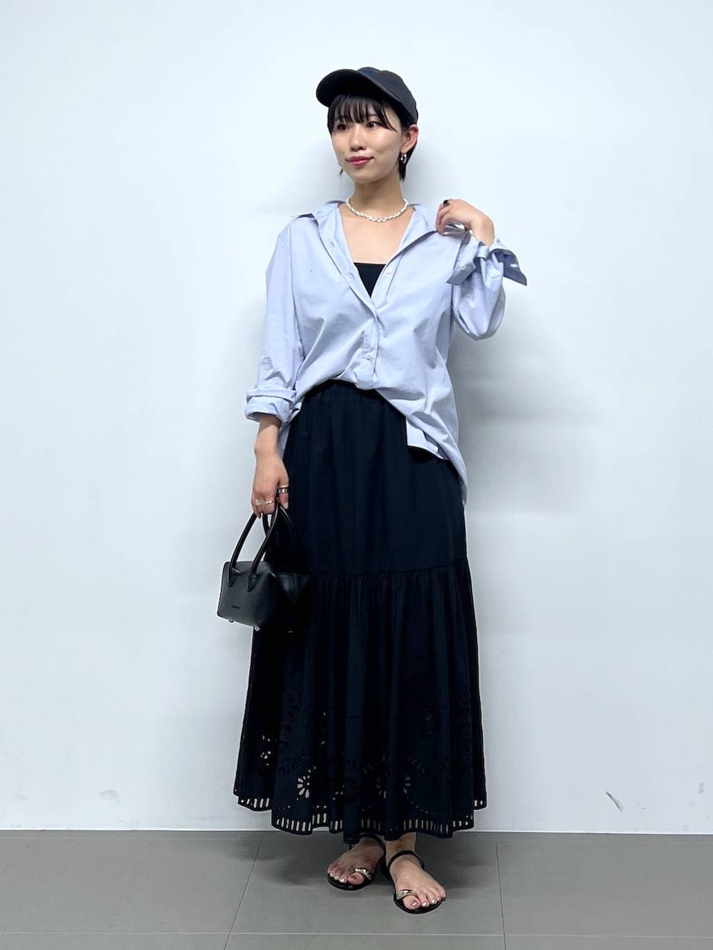 ブラック系のサンダル、ブラック系のハンドバッグ、ブルー系のシャツ/ブラウスを着用したレディースの夏コーディネートの2枚目の写真