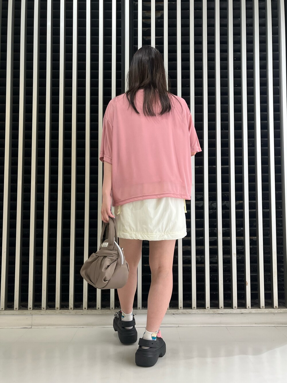 ピンク系のTシャツ/カットソー、ホワイト系のスカート、ベージュ系のショルダーバッグを着用したレディースの夏コーディネートの2枚目の写真