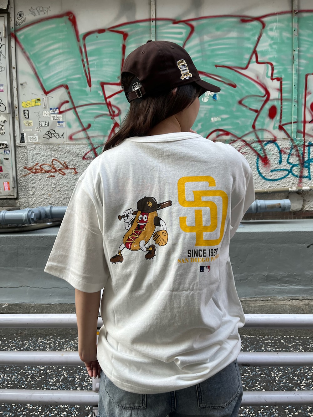 ホワイト系のTシャツ/カットソー、ブルー系のデニムパンツ、ブラウン系のキャップを着用したレディースの夏コーディネートの3枚目の写真