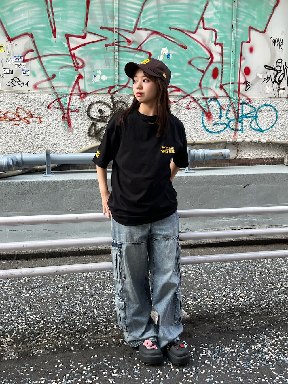 ブルー系のデニムパンツ、ブラック系のTシャツ/カットソー、ブラウン系のキャップを着用したレディースの夏コーディネートの2枚目の写真